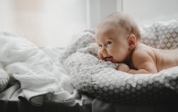 Naked newborn boy lies on the soft blanket before a bright window