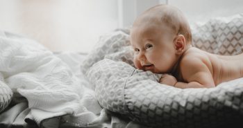 Naked newborn boy lies on the soft blanket before a bright window